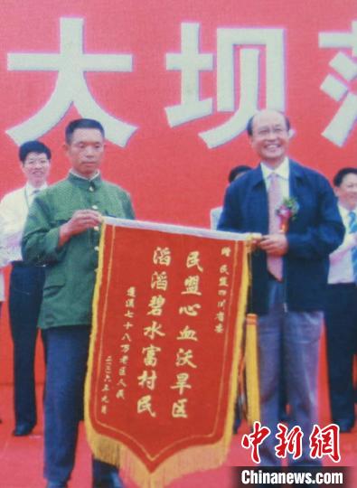2006年9月,在黑龙凼水库大坝落成仪式上,吴正德(右一)代表民盟四川省接受库区百姓赠送锦旗。 张焰刚 摄