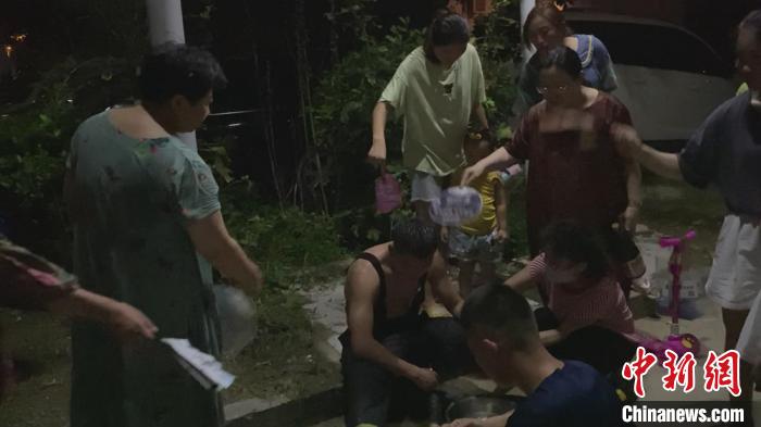 有几名热心人围过来不停地为该消防员扇扇子降温。 徐州市消防救援支队供图 摄