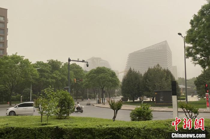 图为位于西安市曲江新区的一处街道,远处的建筑在沙尘中若隐若现。 张一辰 摄