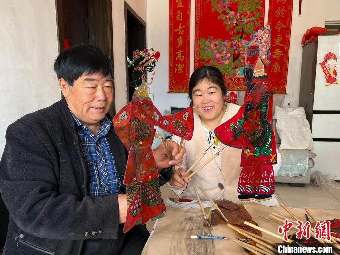 图为冯克献和女儿展示制作完成的皮影道具。 马瑾 摄