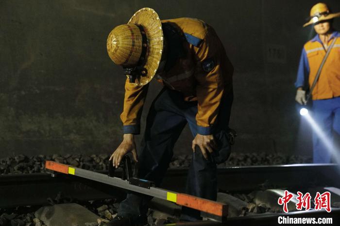 图为线路工用手工电子道尺检查铁轨。 吴宇 摄